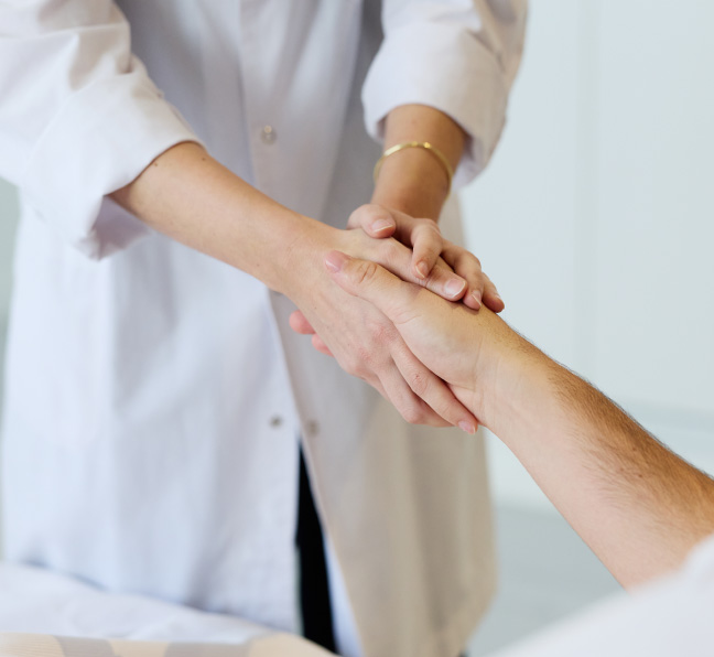 Profesional de la salud sosteniendo la mano de un paciente durante su atención médica