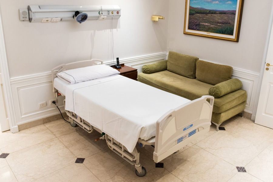Habitación individual de internación con cama hospitalaria, sofá para acompañante y ambiente confortable